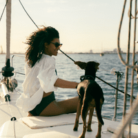 Black dog facing a lady in white white on a boat